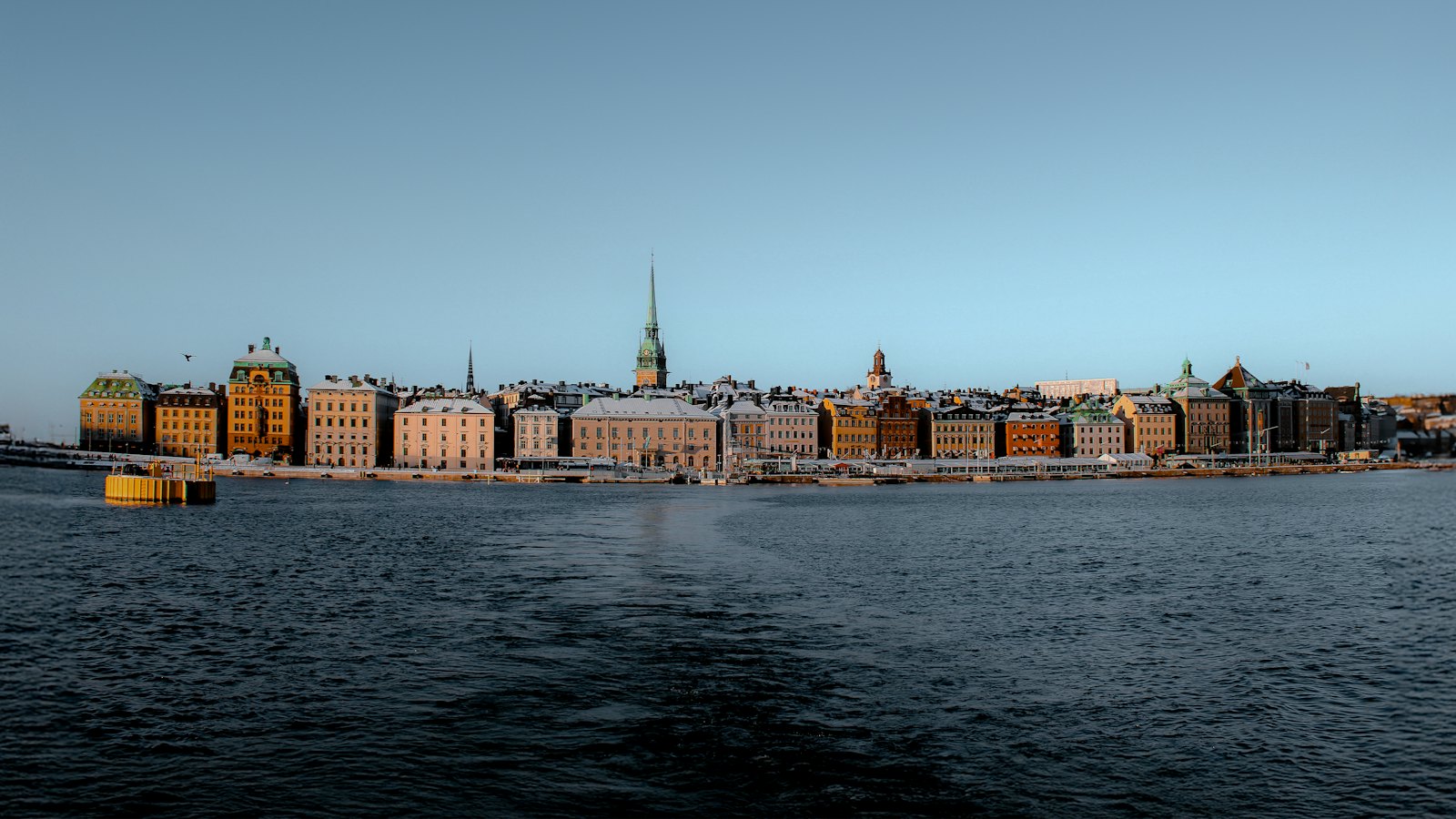 Gamla Stan's colorful waterfront skyline and church spire at dusk in Stockholm