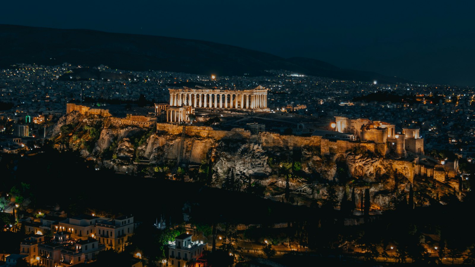 The illuminated Parthenon atop the Acropolis rock glowing above Athens at night