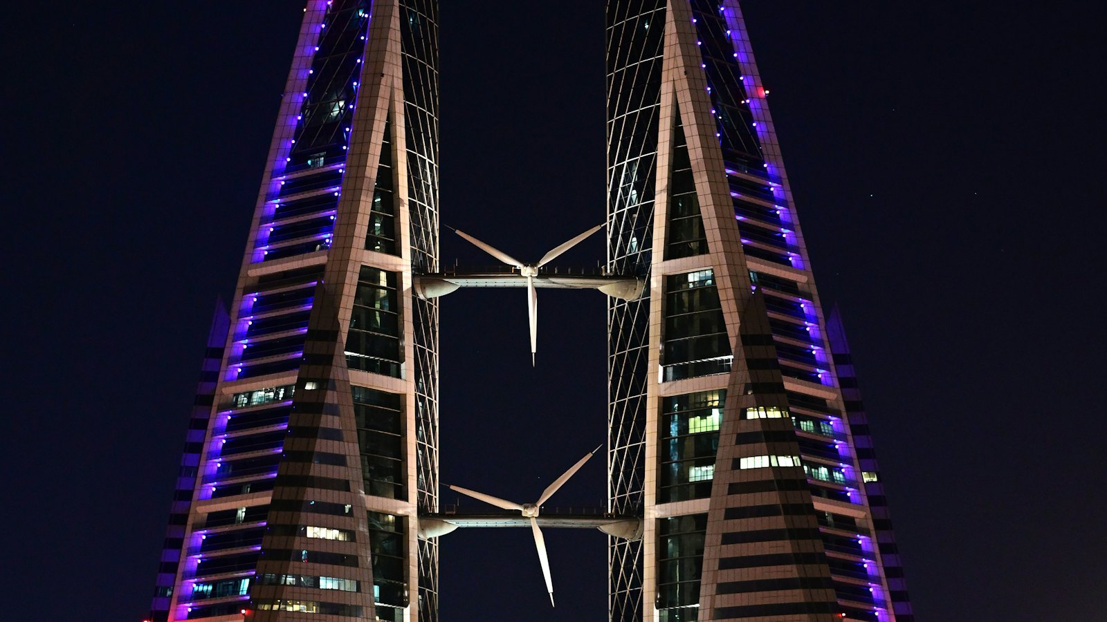 Bahrain World Trade Center's twin sail towers and wind turbines lit up at night