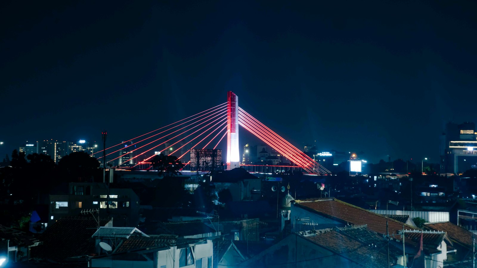 Pasupati Bridge in Bandung glowing red at night above the city's dark rooftops