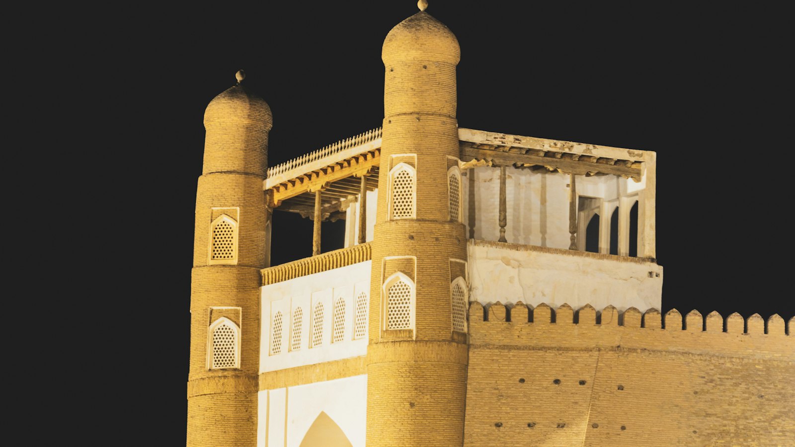 Historic floodlit gate towers of Bukhara's old city glowing against the night sky