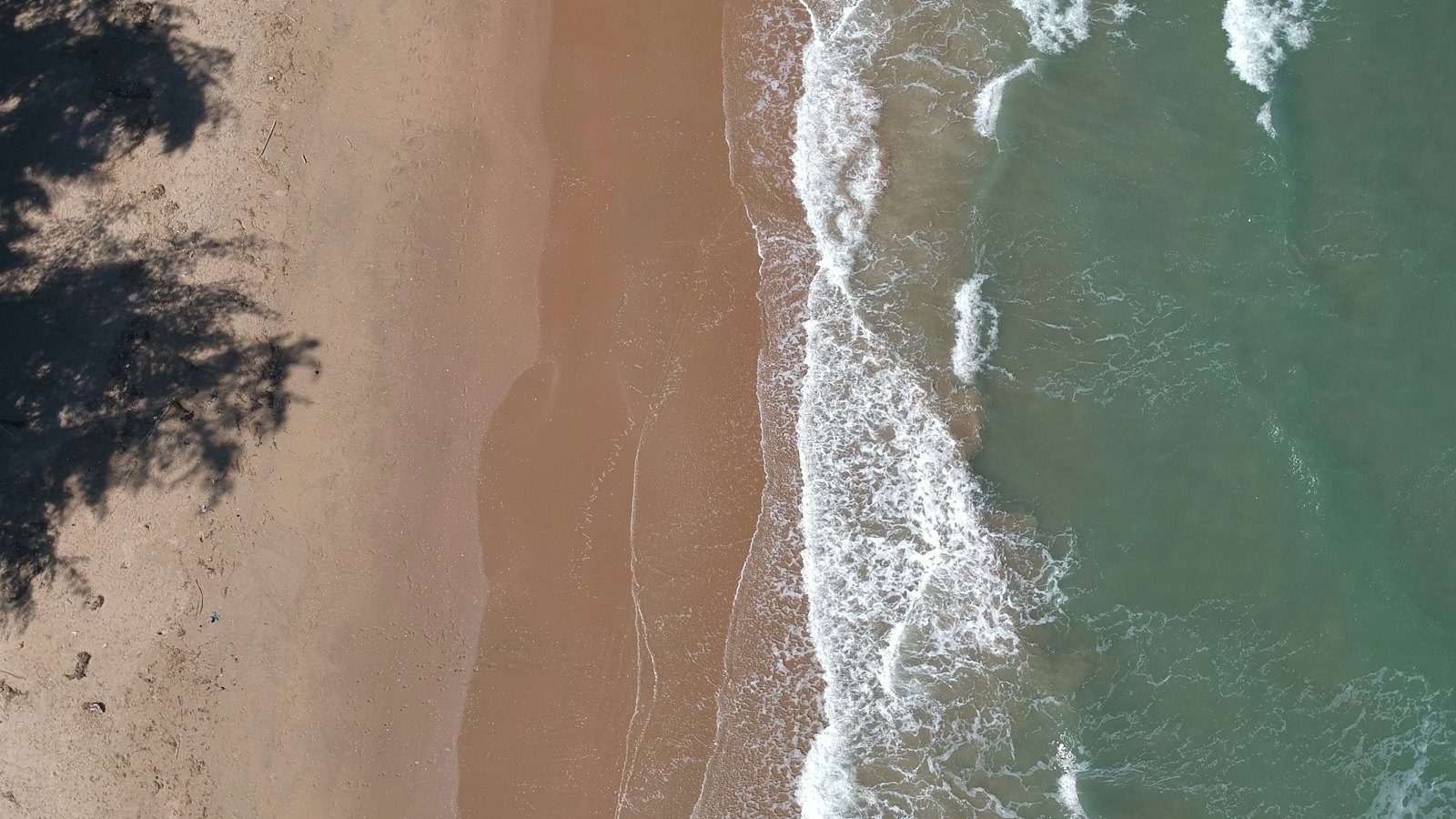 Turquoise waves washing over a sandy beach on Hua Hin's coast