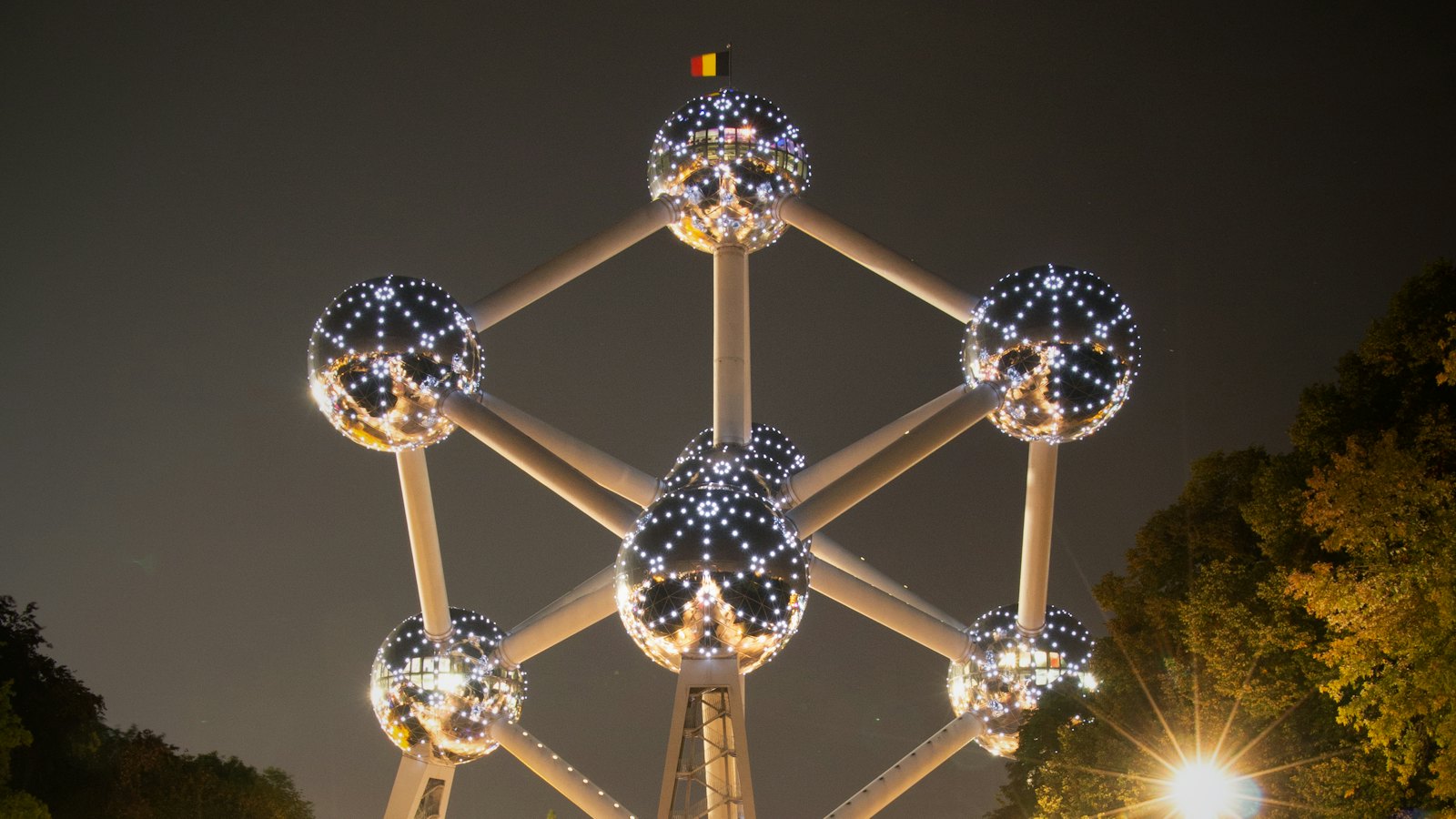 The illuminated Atomium sculpture glowing above a Brussels park at night