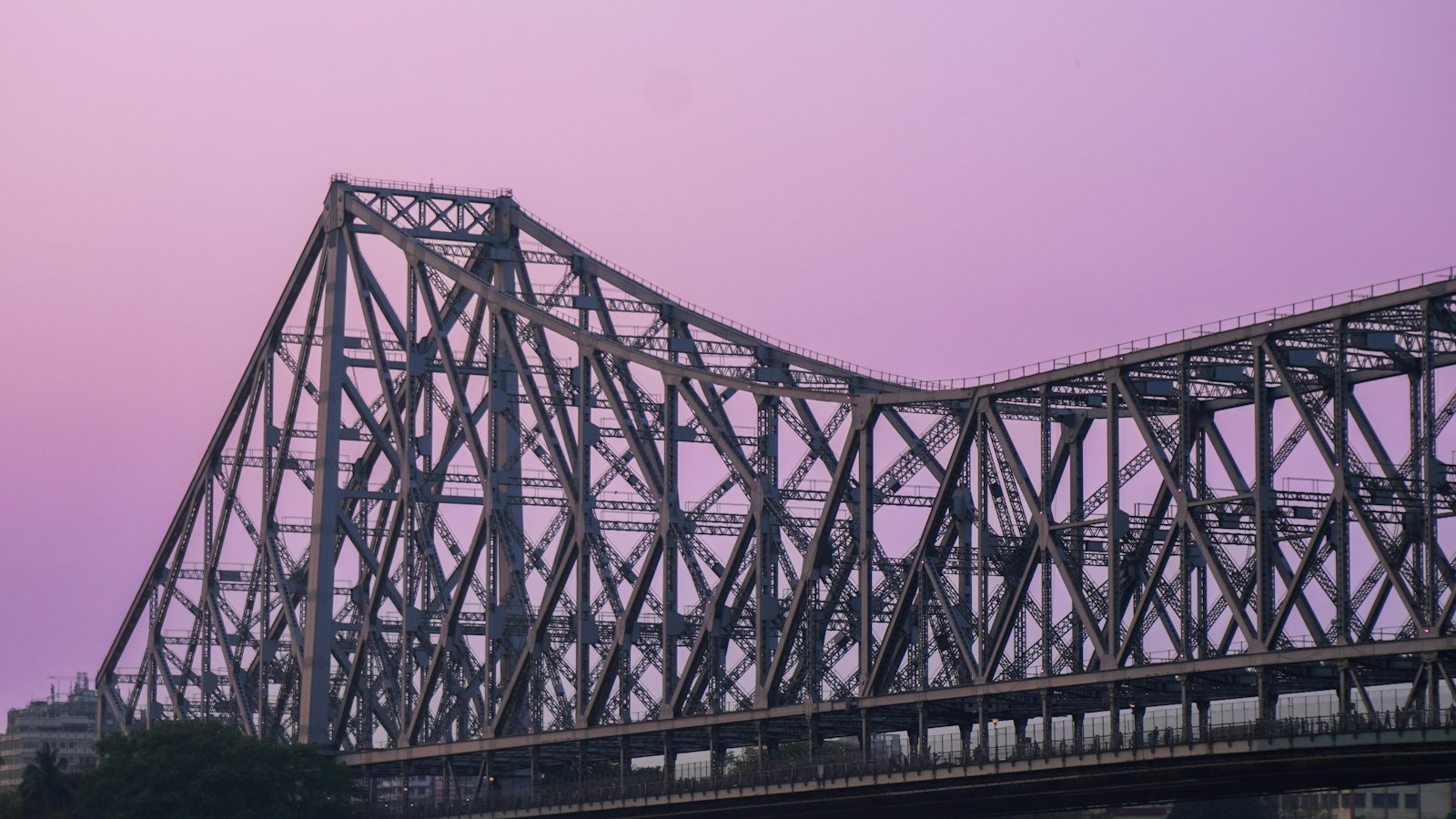 Howrah Bridge's steel cantilever trusses silhouetted against a purple dusk sky in Kolkata
