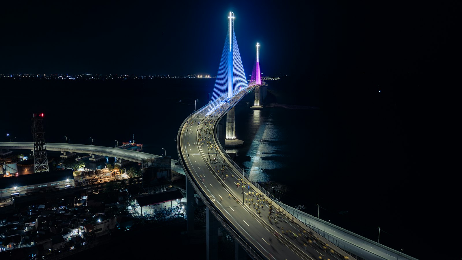 Cebu-Cordova Link Expressway bridge pylons glowing blue and pink at night over Mactan Channel, Cebu