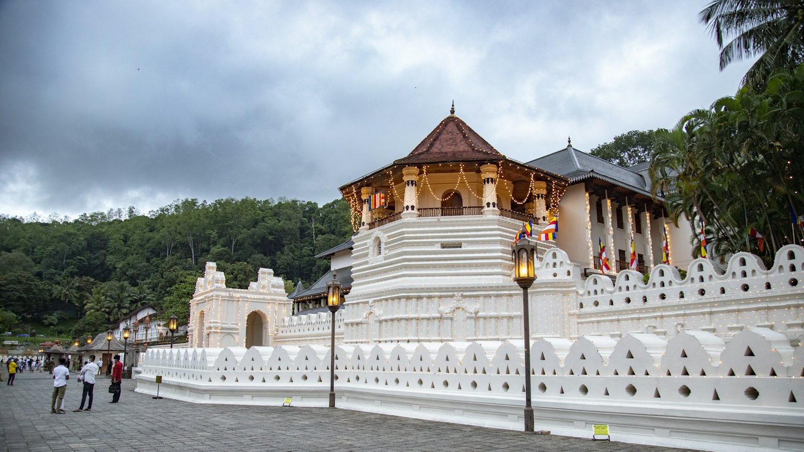 The gold-roofed Temple of the Tooth glowing with string lights at dusk in Kandy