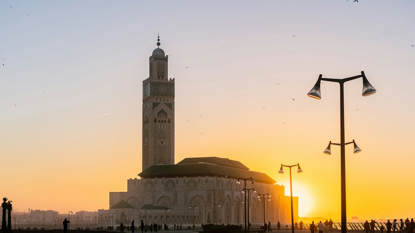 The Hassan II Mosque silhouetted against a golden sunset in Casablanca