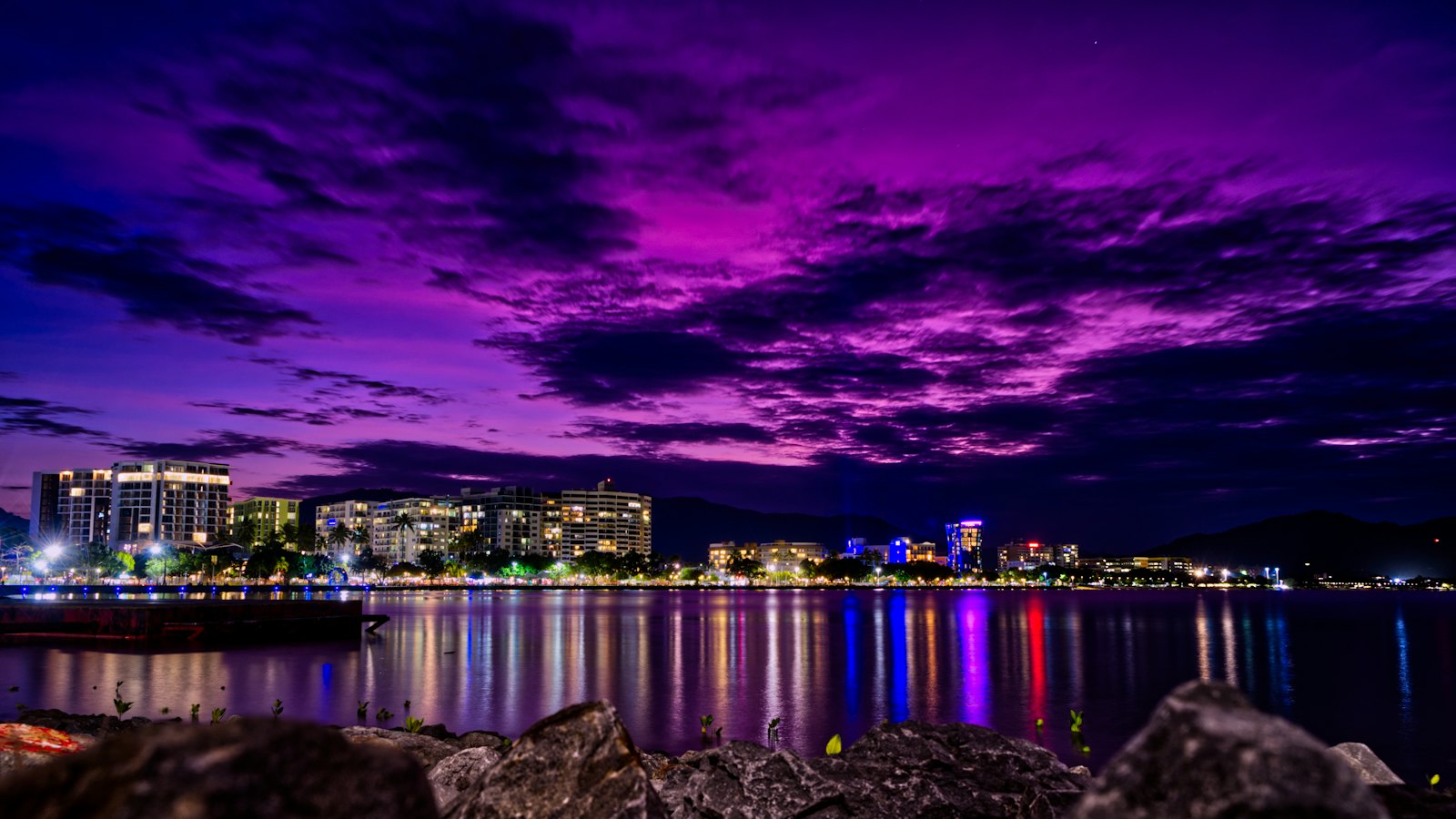 Purple dusk sky over the Cairns Esplanade skyline reflected in calm water