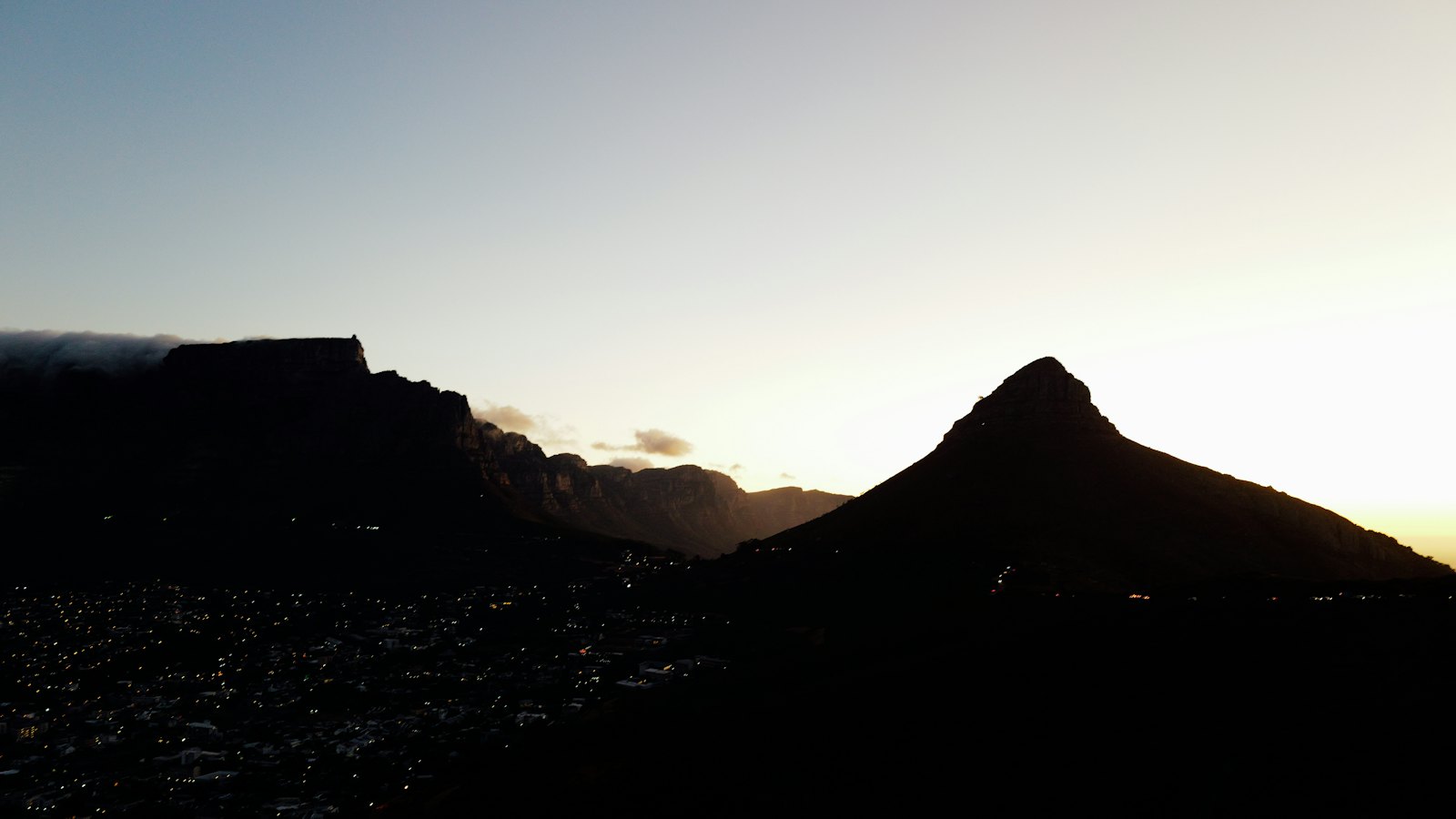 Table Mountain and Lion's Head silhouetted at dusk above the lights of Cape Town