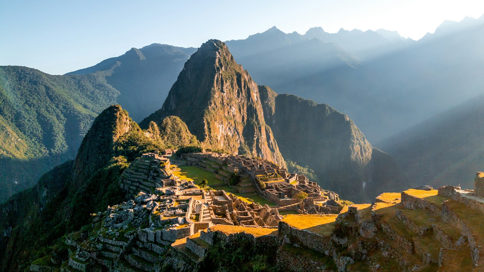 Golden sunrise light striking the Machu Picchu ruins and Huayna Picchu peak