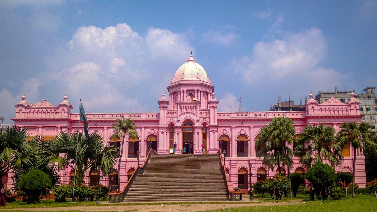 Ahsan Manzil pink palace with its central dome framed by palm trees in Dhaka