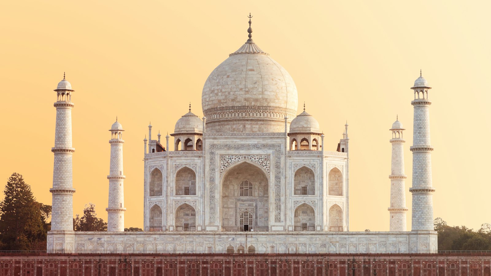 The Taj Mahal's white marble dome glowing under a warm sunset sky in Agra