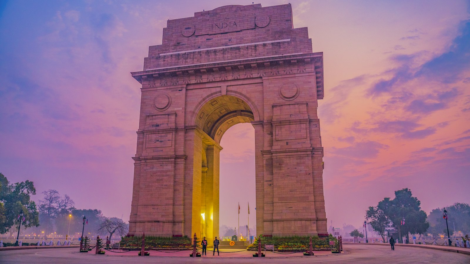 India Gate war memorial in New Delhi under a pink and violet dusk sky