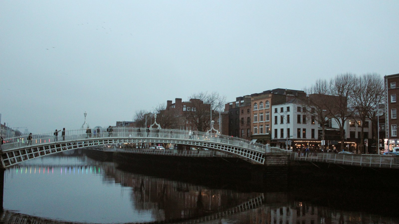 The white cast-iron Ha'penny Bridge arching over the River Liffey in Dublin at dusk