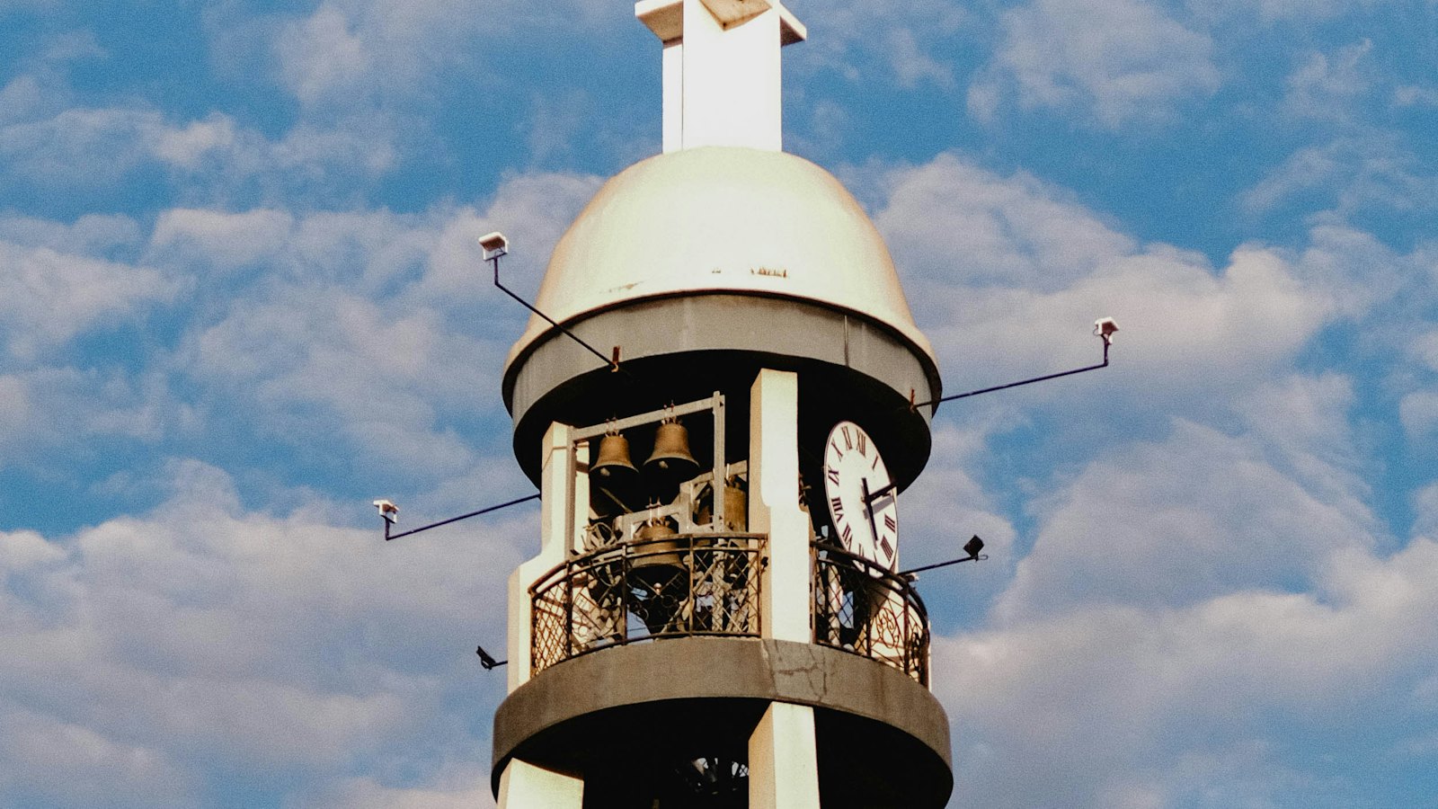 San Pedro Cathedral's bell tower with clock and cross against a golden sky in Davao