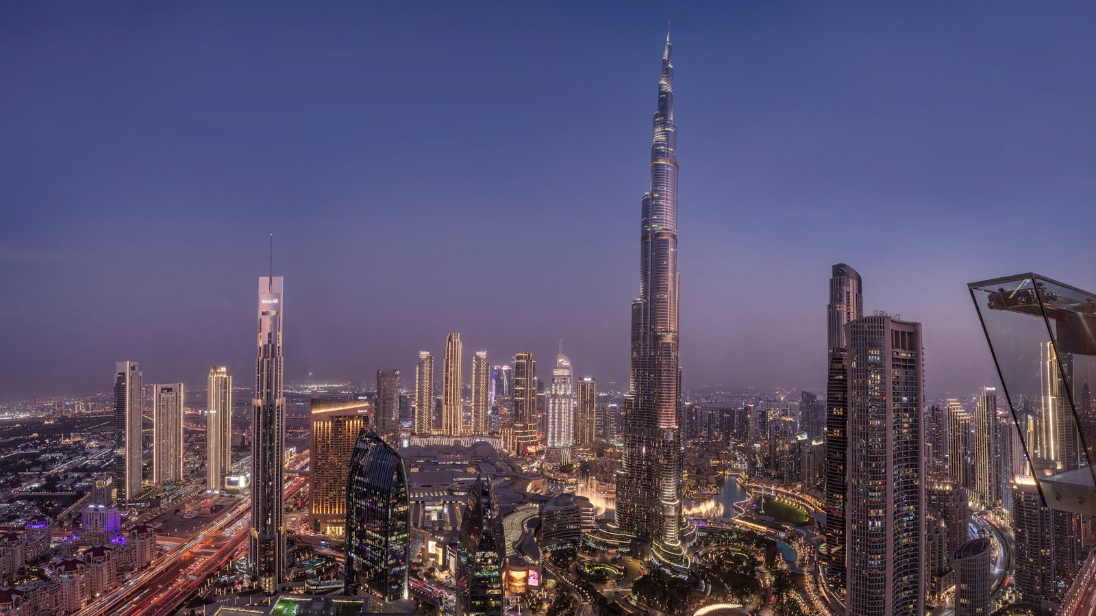 Burj Khalifa rising over Downtown Dubai skyscrapers and the Dubai Fountain lake at twilight