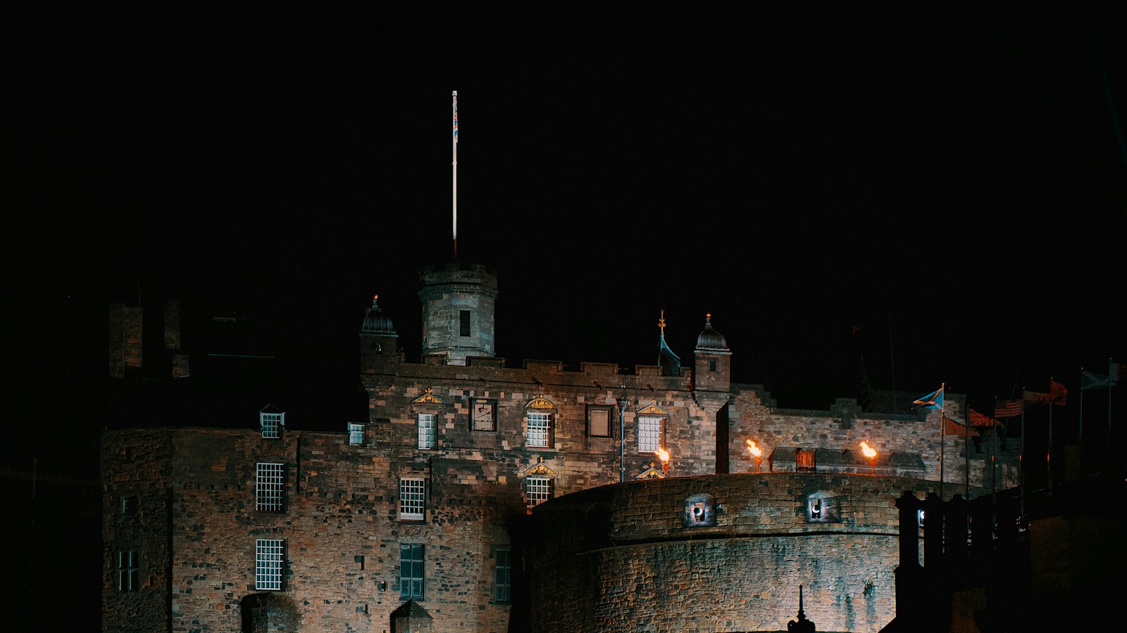 Edinburgh Castle illuminated at night atop its rocky crag above the old town