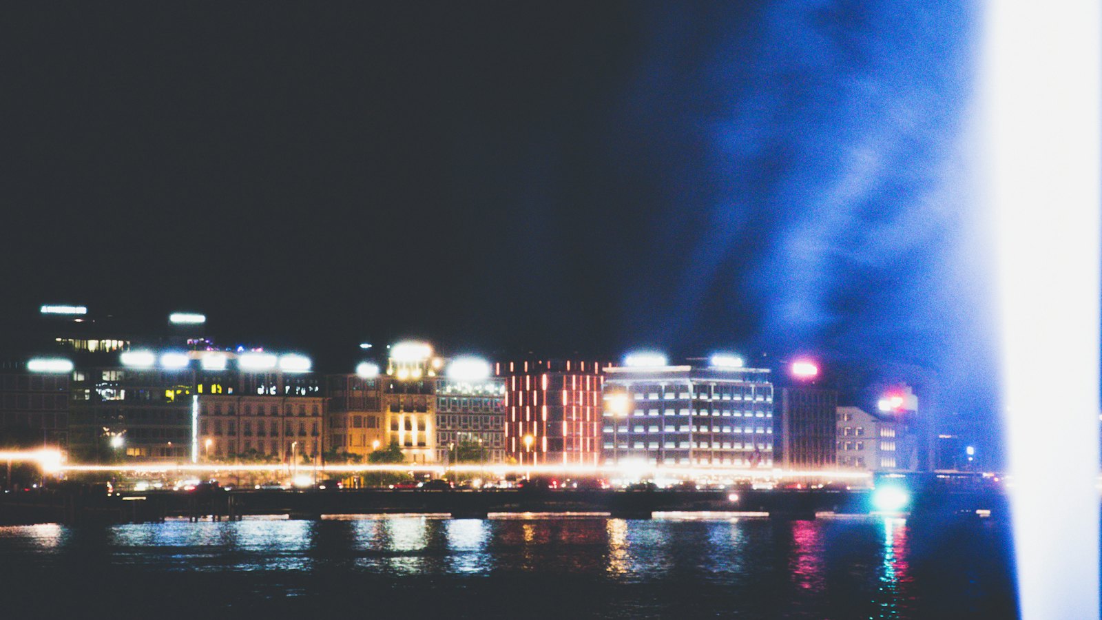 Geneva's illuminated lakefront skyline at night beside the spray of the Jet d'Eau