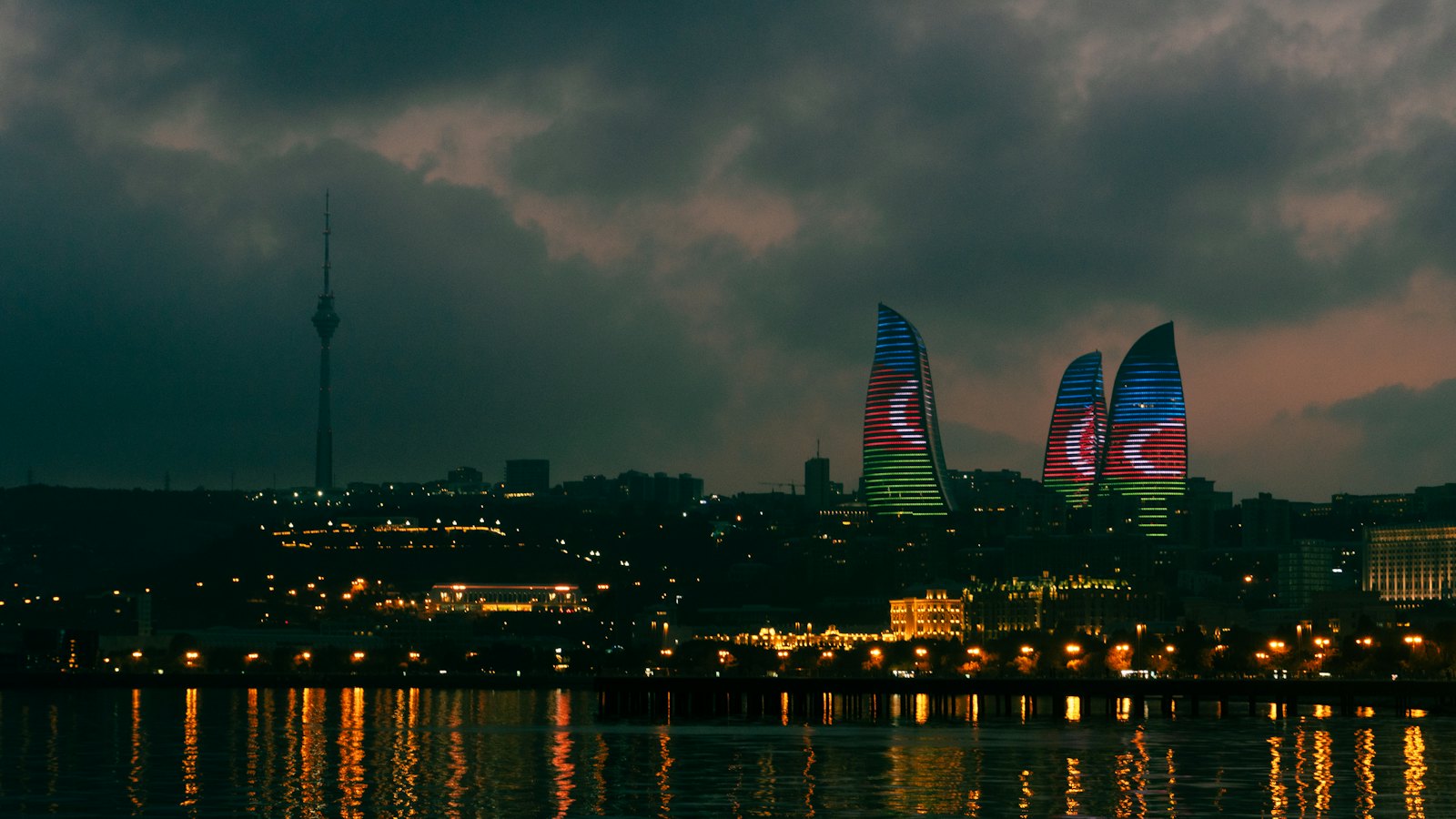Baku's Flame Towers illuminated at night with reflections on the waterfront