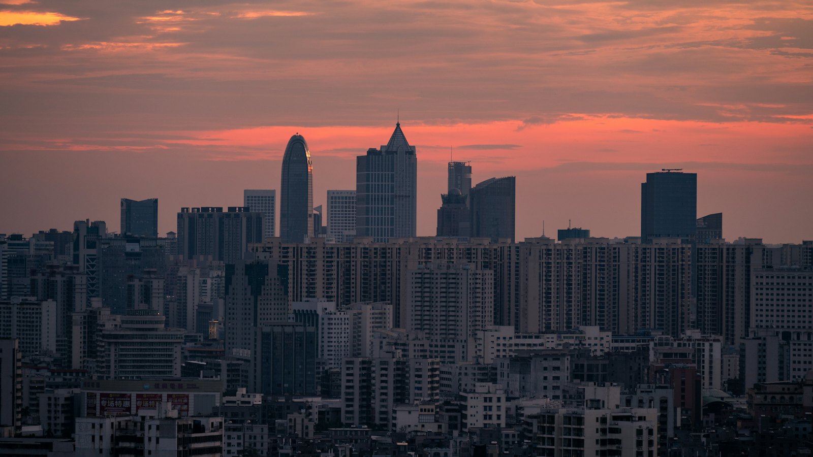 Haikou's skyline silhouettes against a vivid orange and pink sunset sky