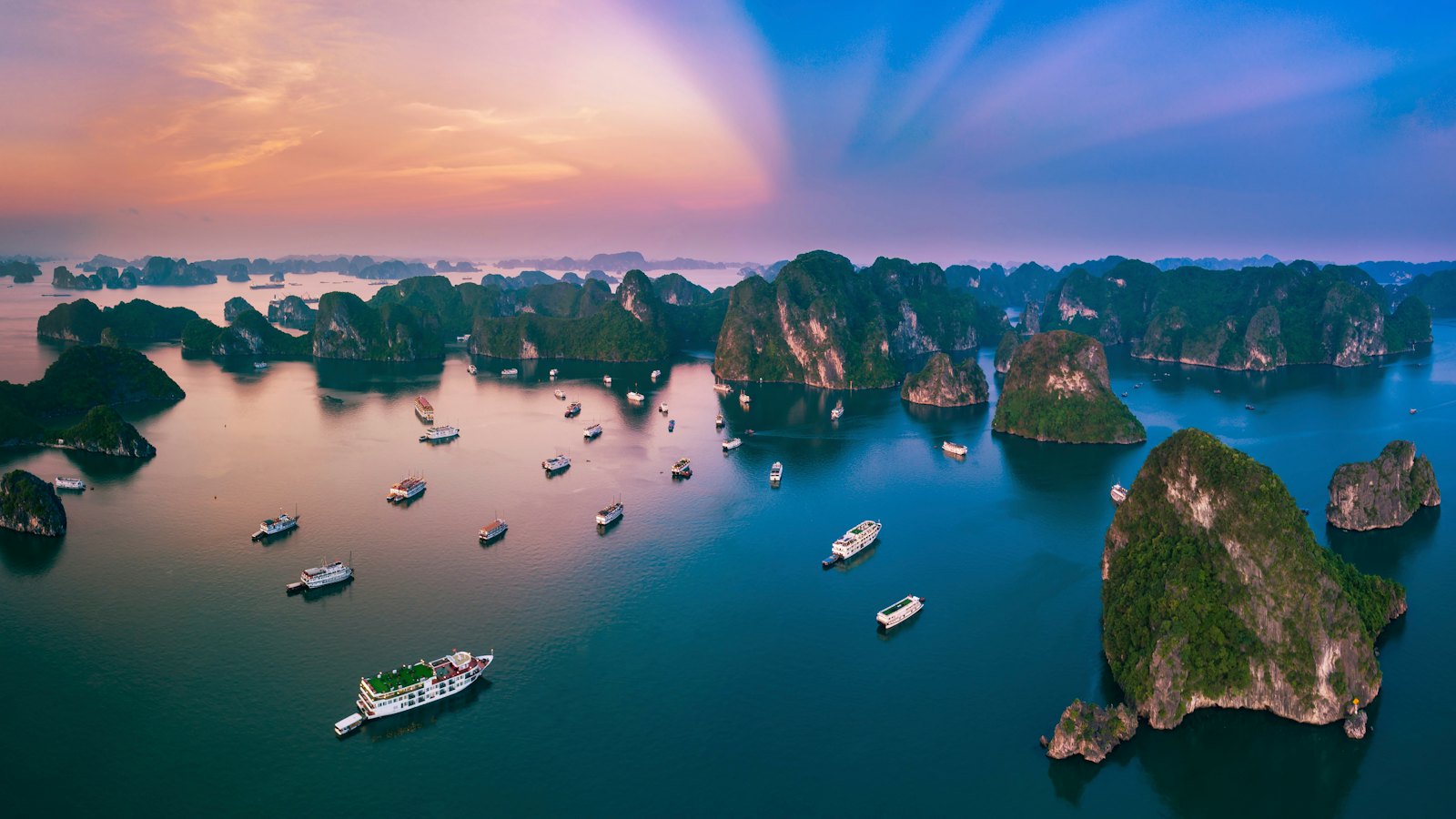 Limestone karst islands scattered across Ha Long Bay at sunset