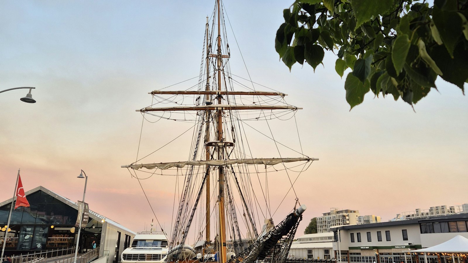 A historic tall ship moored at Hobart's waterfront under a pastel dusk sky