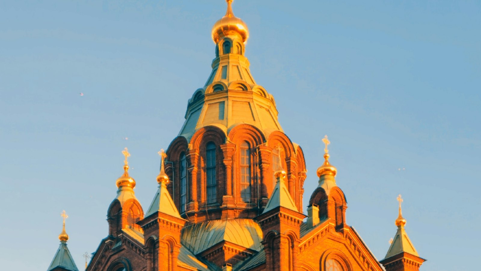 Uspenski Cathedral's golden domes glowing at sunset above Helsinki's harbor district