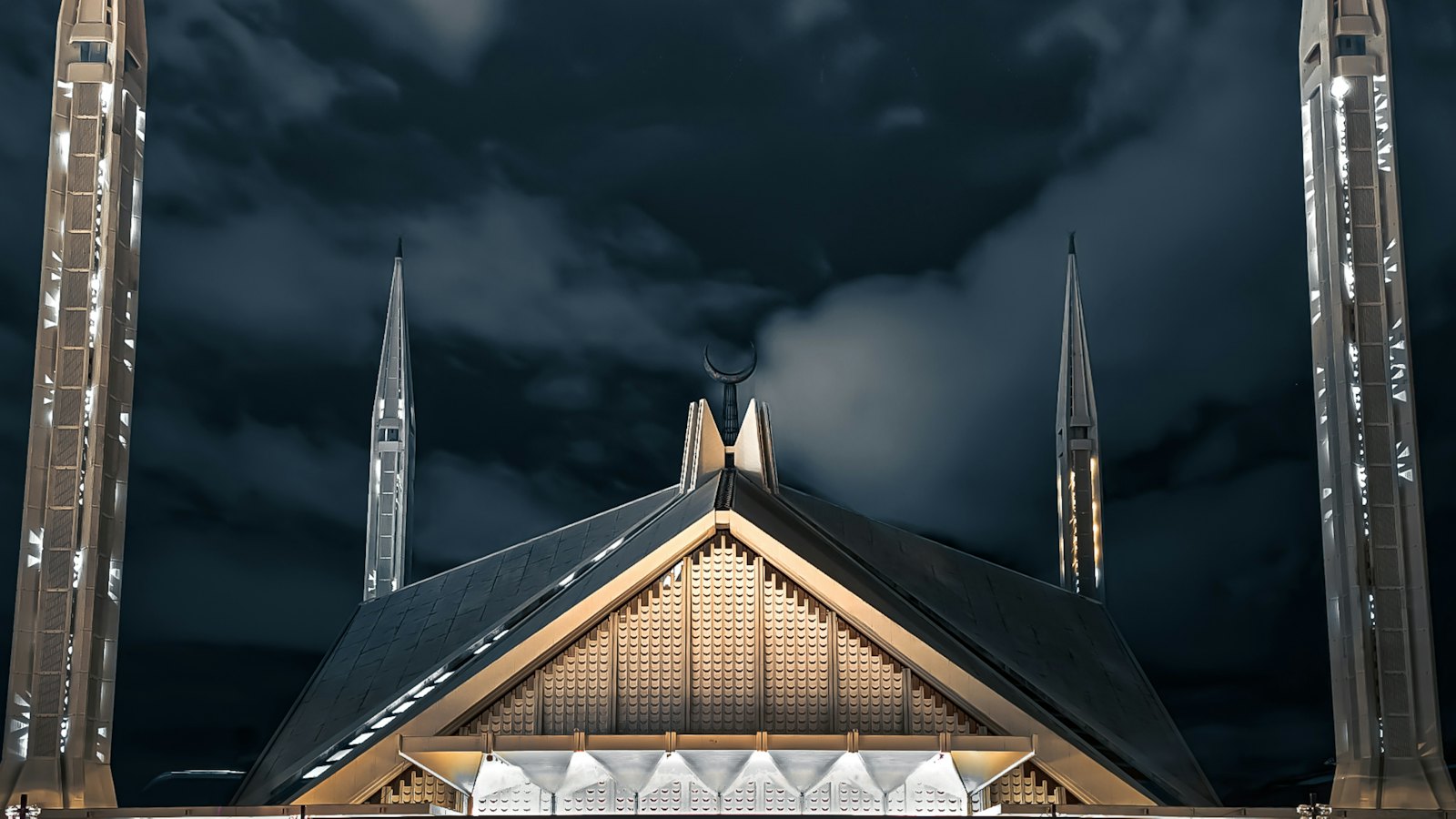 Faisal Mosque's triangular hall and twin minarets lit at night in Islamabad
