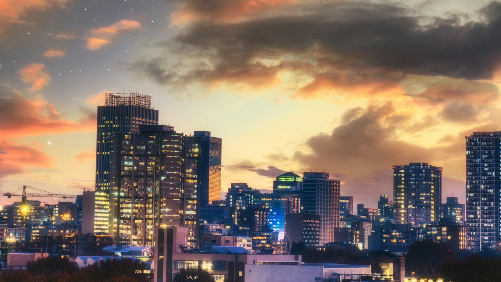 Johannesburg's skyline glowing beneath a dramatic dusk sky with stars appearing