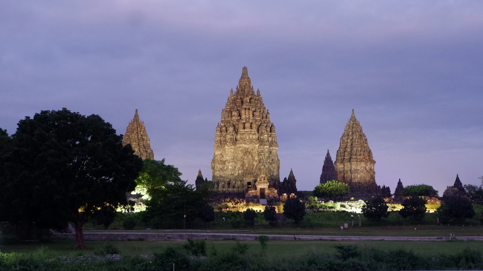 Floodlit spires of Prambanan Temple near Yogyakarta at dusk under a violet twilight sky