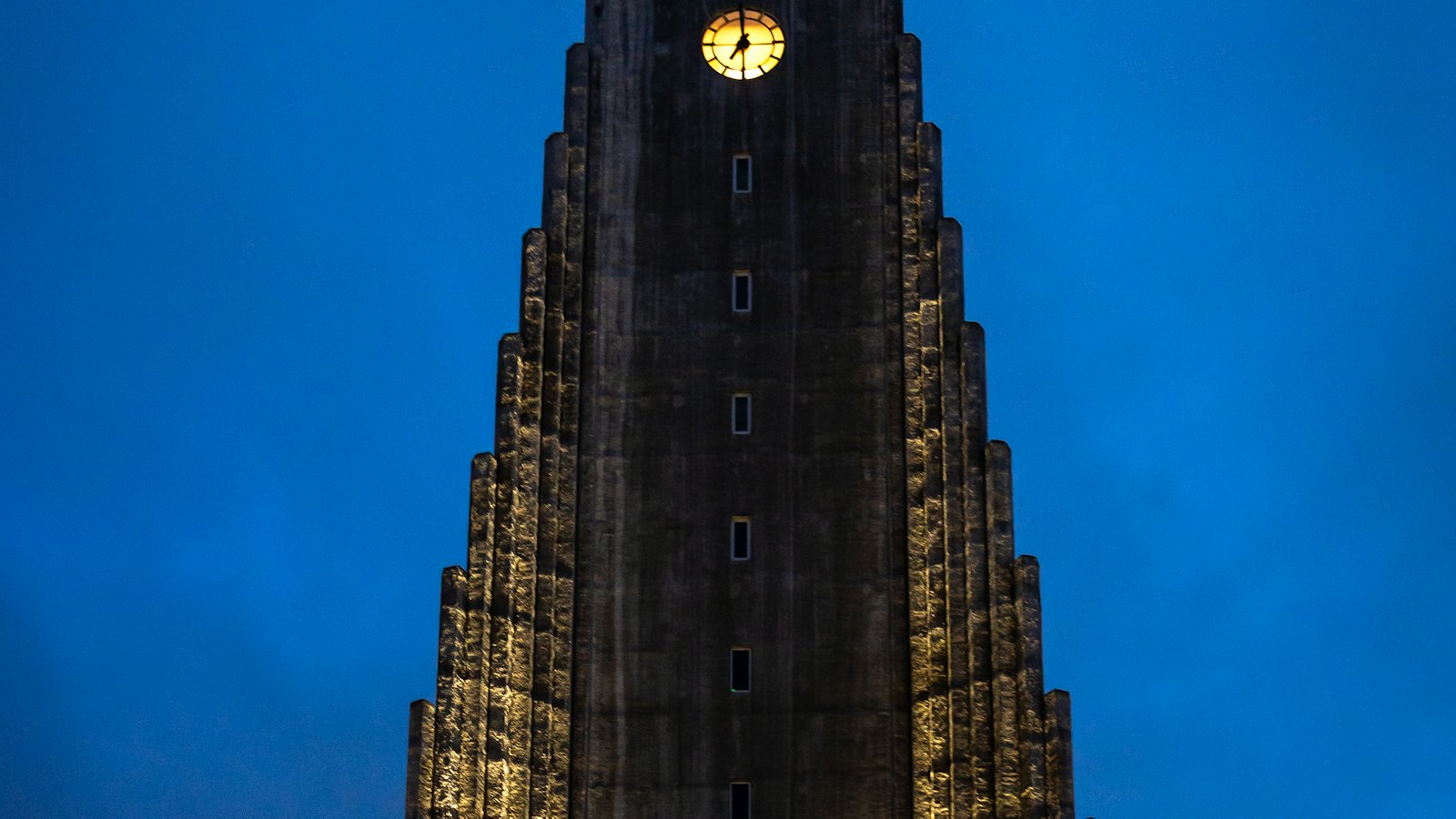 Hallgrimskirkja's towering facade illuminated against a deep blue dusk sky in Reykjavik