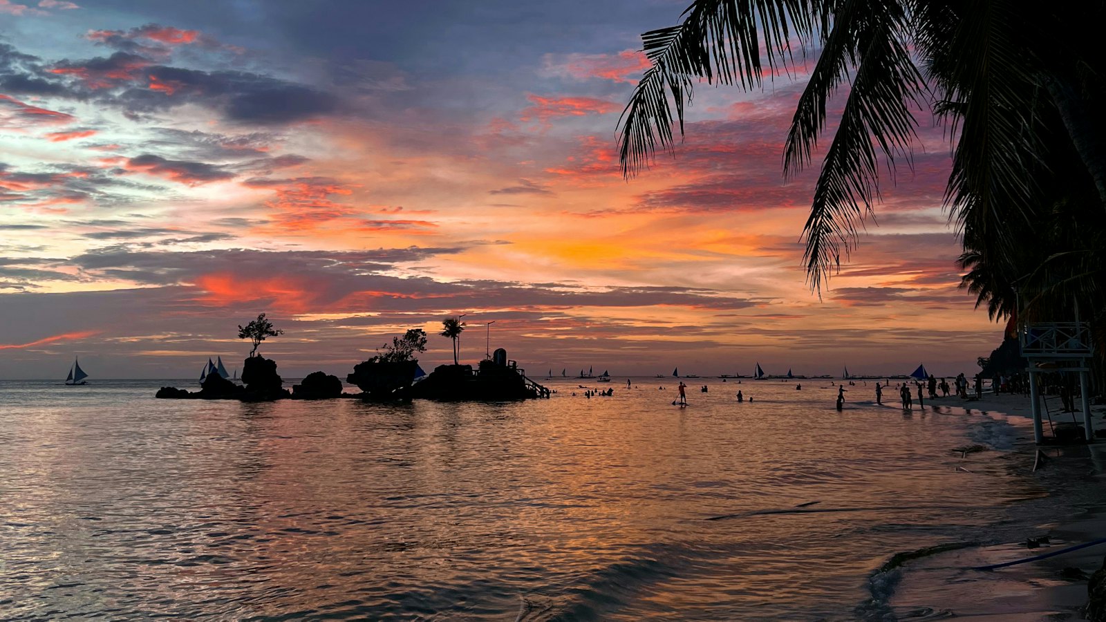 Willy's Rock silhouetted against a pink dusk sky on White Beach, Boracay, Philippines