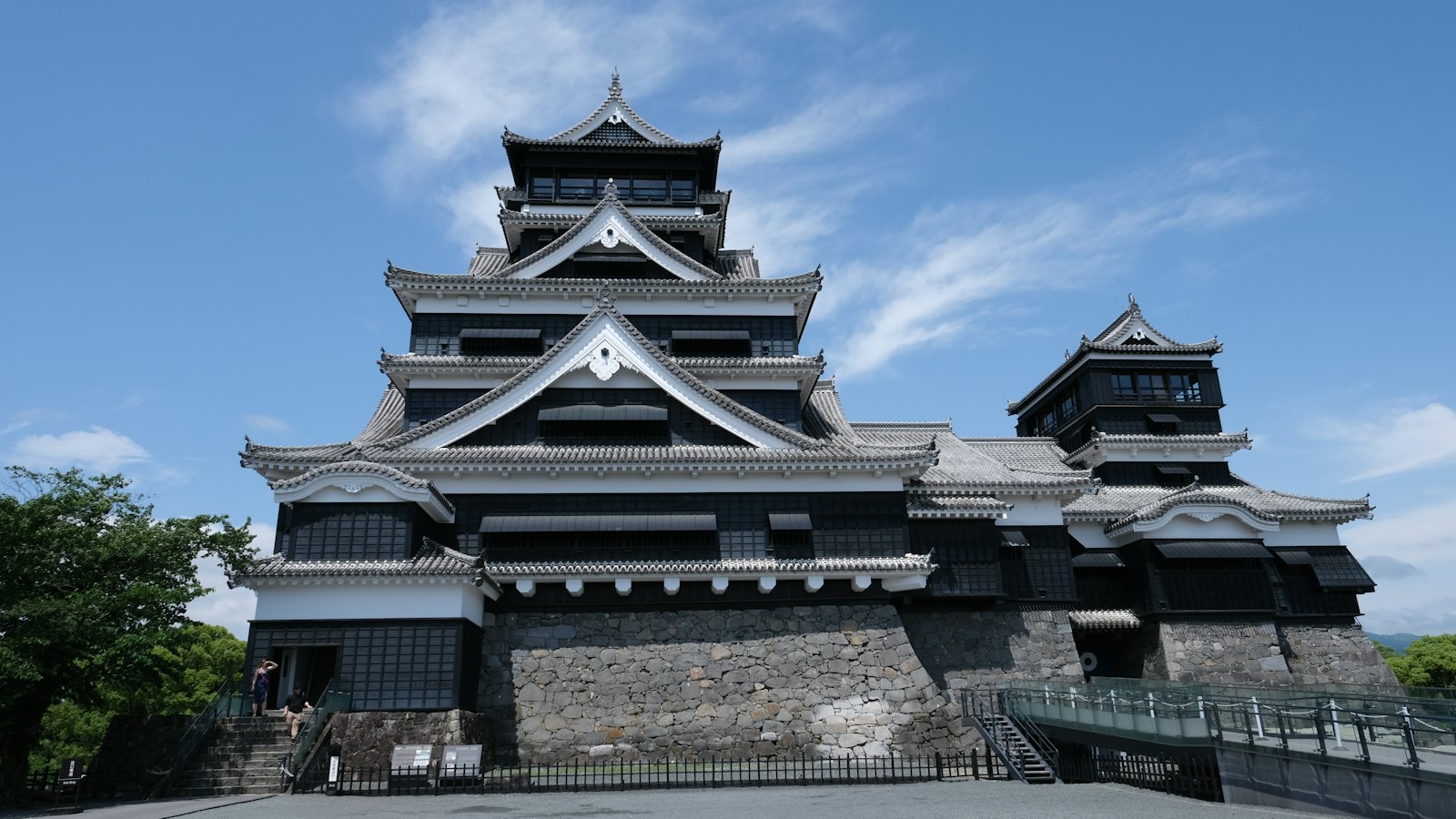 Kumamoto Castle's tiered black and white keep rising against a blue sky