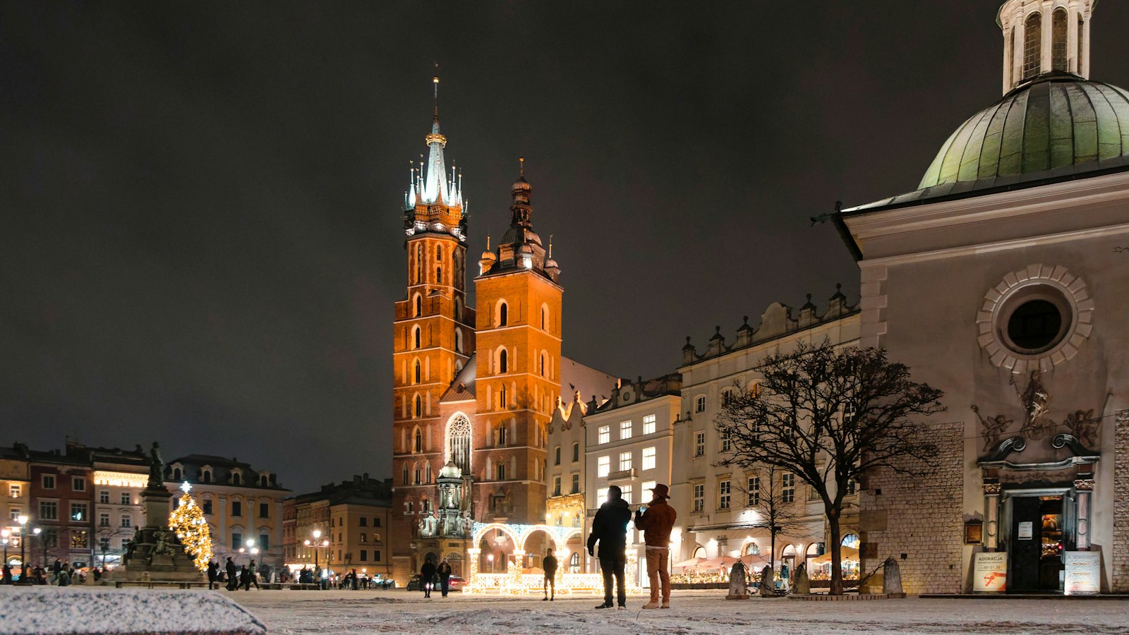 St Mary's Basilica towers lit up above a snowy Krakow Main Square at night
