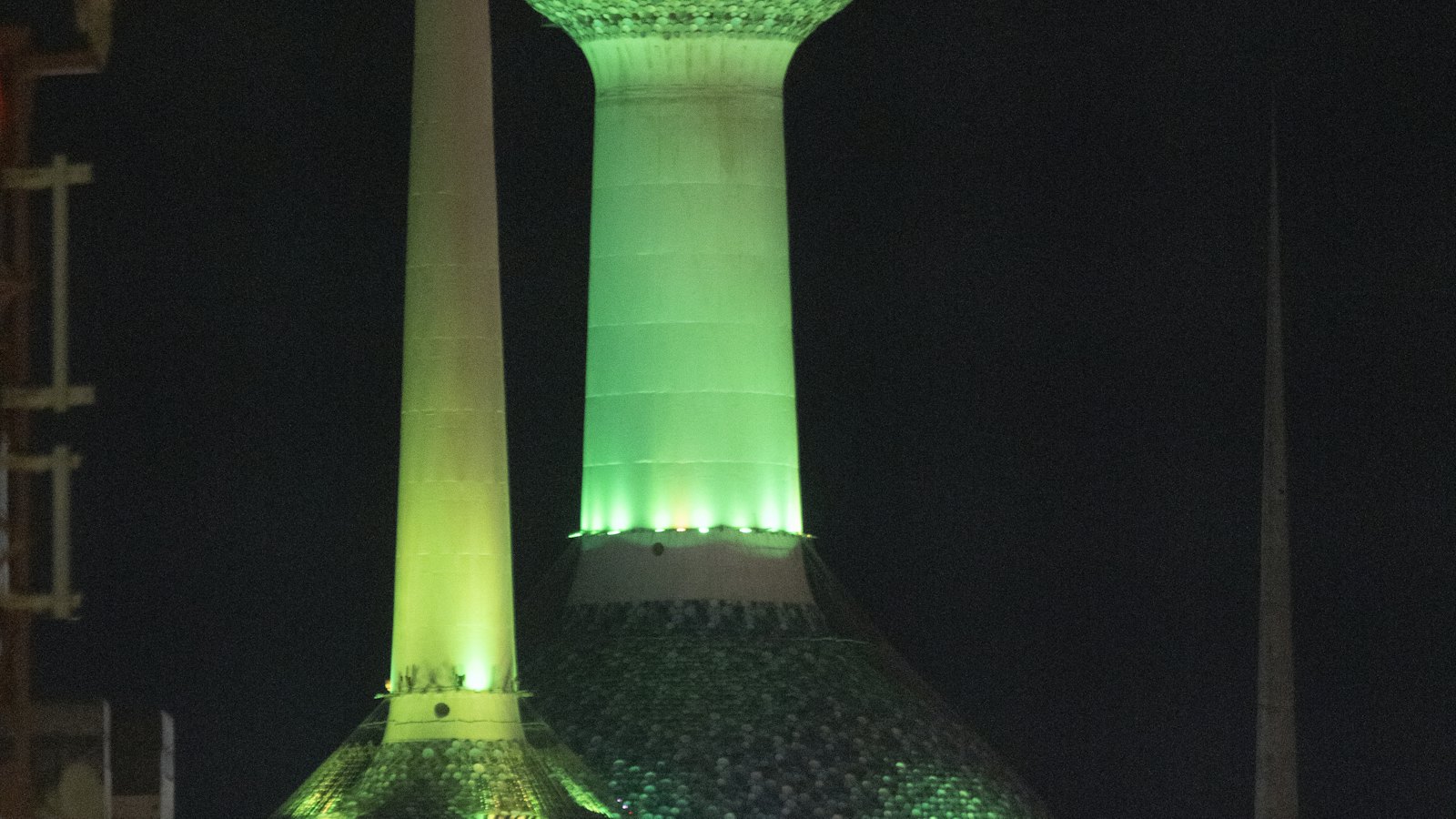 Kuwait Towers' mosaic spheres glowing green against the night sky in Kuwait City