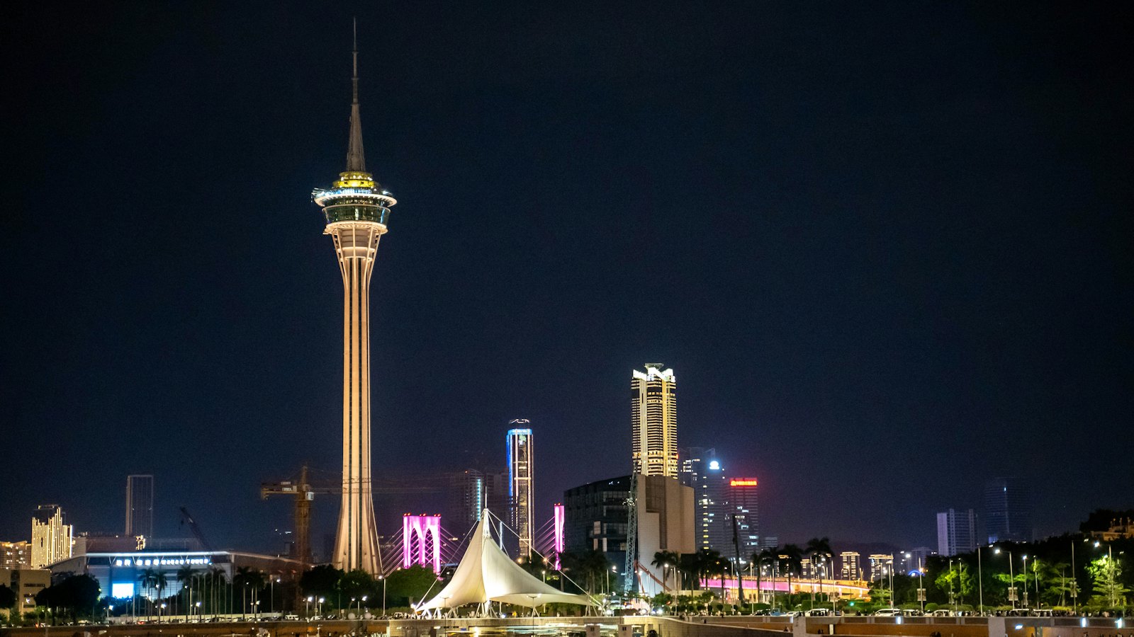 Macau Tower lit gold at night over the waterfront skyline and its reflections, Macau