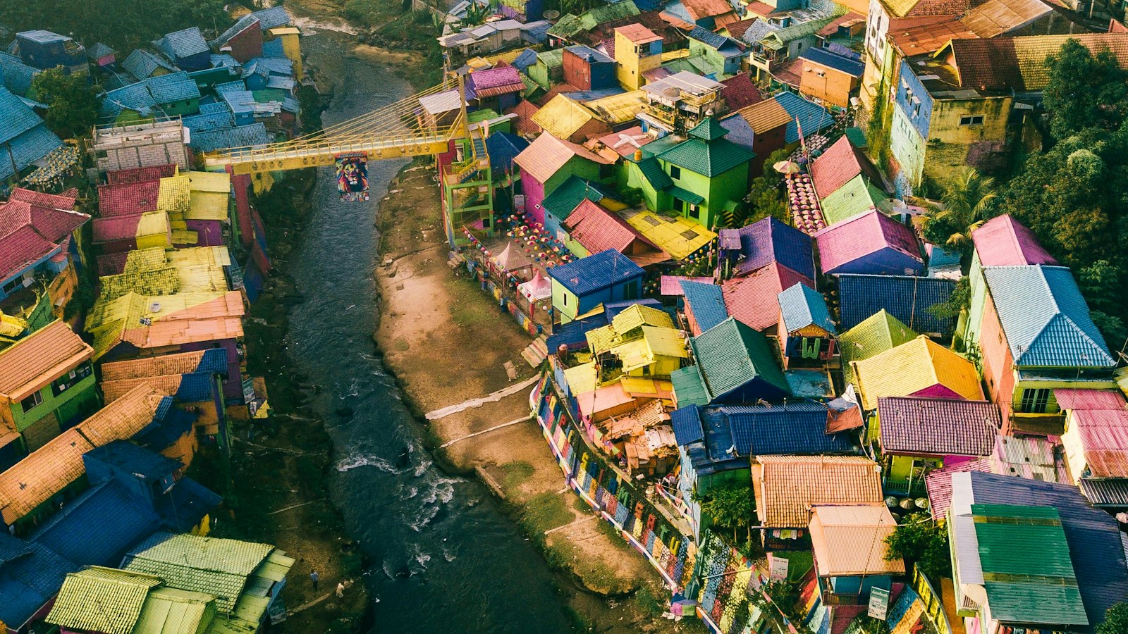 Aerial view of Kampung Warna-Warni's rainbow rooftops lining the river in Malang