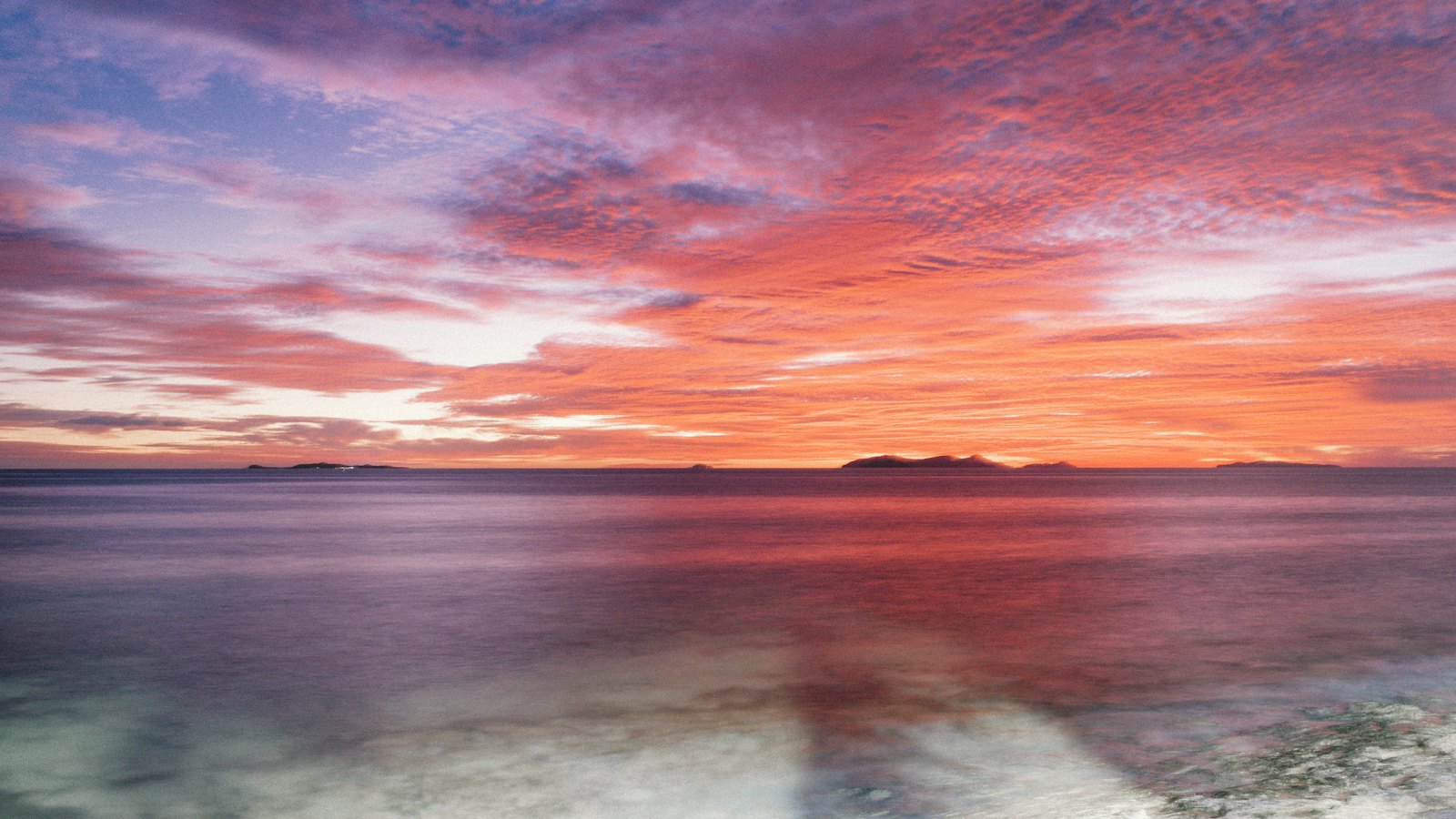 A fiery pink and orange sunset over Beachcomber Island in Fiji