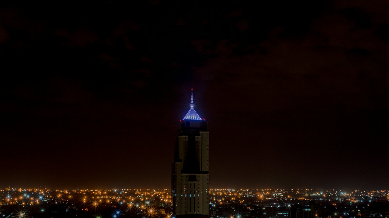 A tall illuminated tower rising above Nairobi's glowing skyline at night