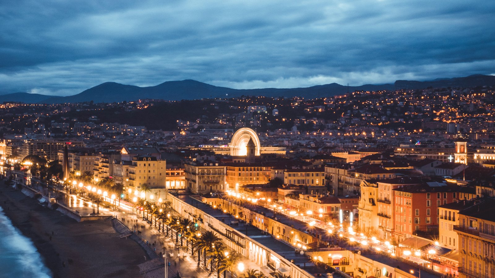 Aerial view of the illuminated Promenade des Anglais curving along the Bay of Nice at dusk