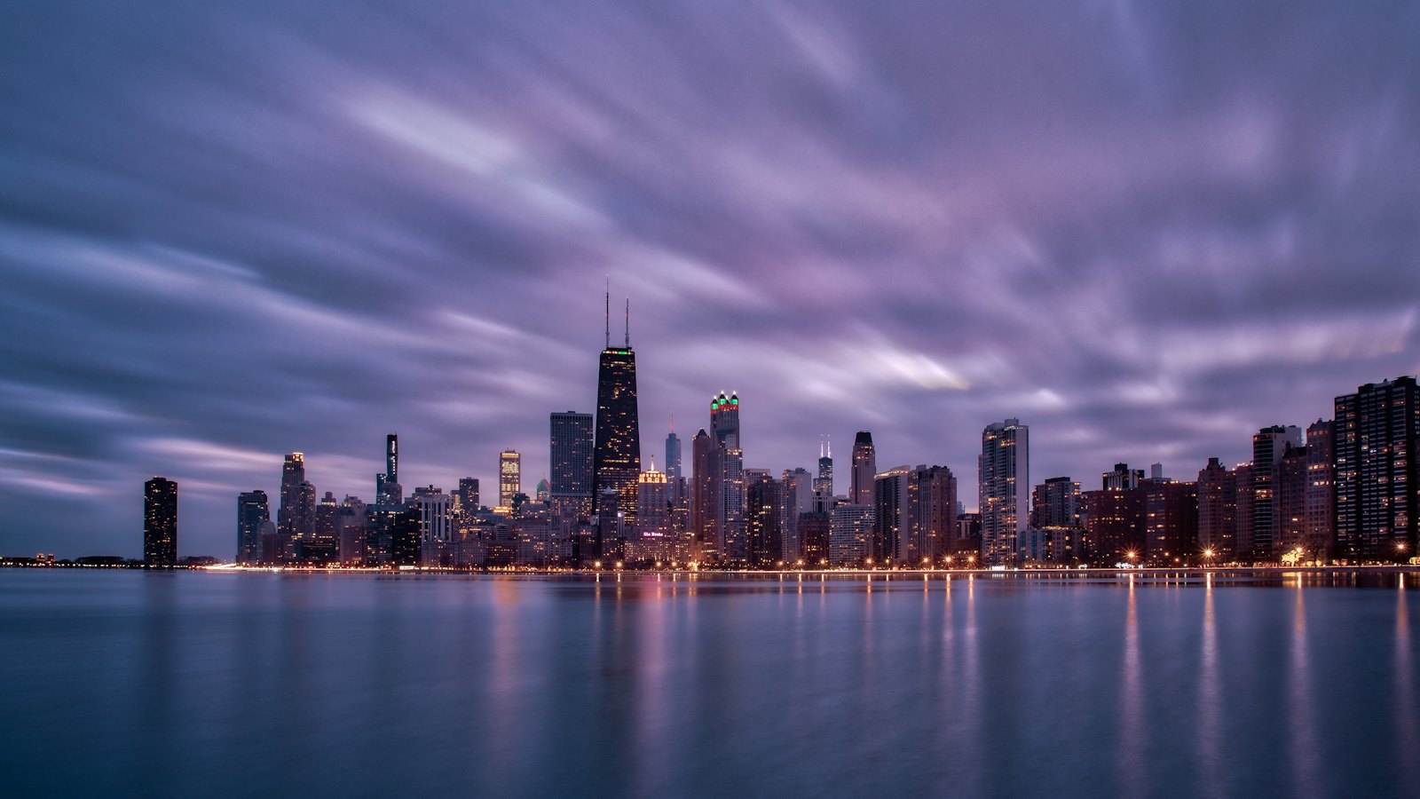 The Chicago skyline glowing at blue hour across Lake Michigan from North Avenue Beach