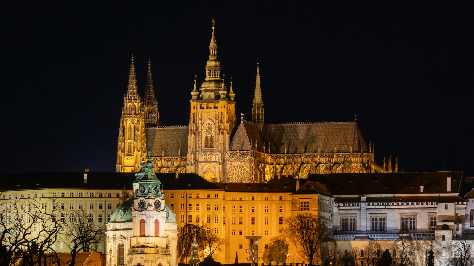 St. Vitus Cathedral and Prague Castle glowing gold against a black night sky in Prague