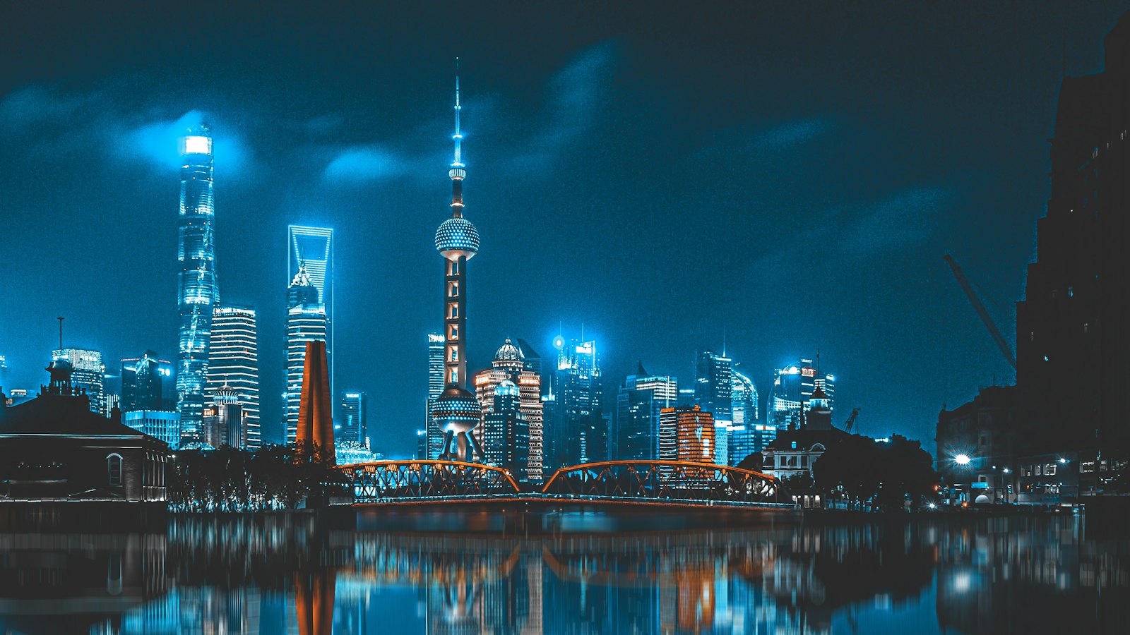 Oriental Pearl Tower and Lujiazui skyline glowing blue at night behind Waibaidu Bridge, Shanghai