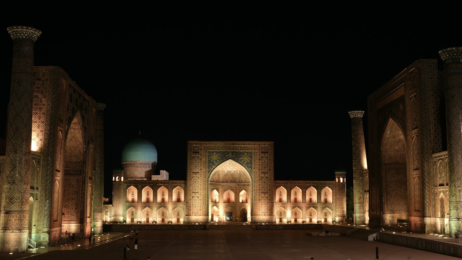 The Registan's illuminated madrasas and towering portals at night in Samarkand