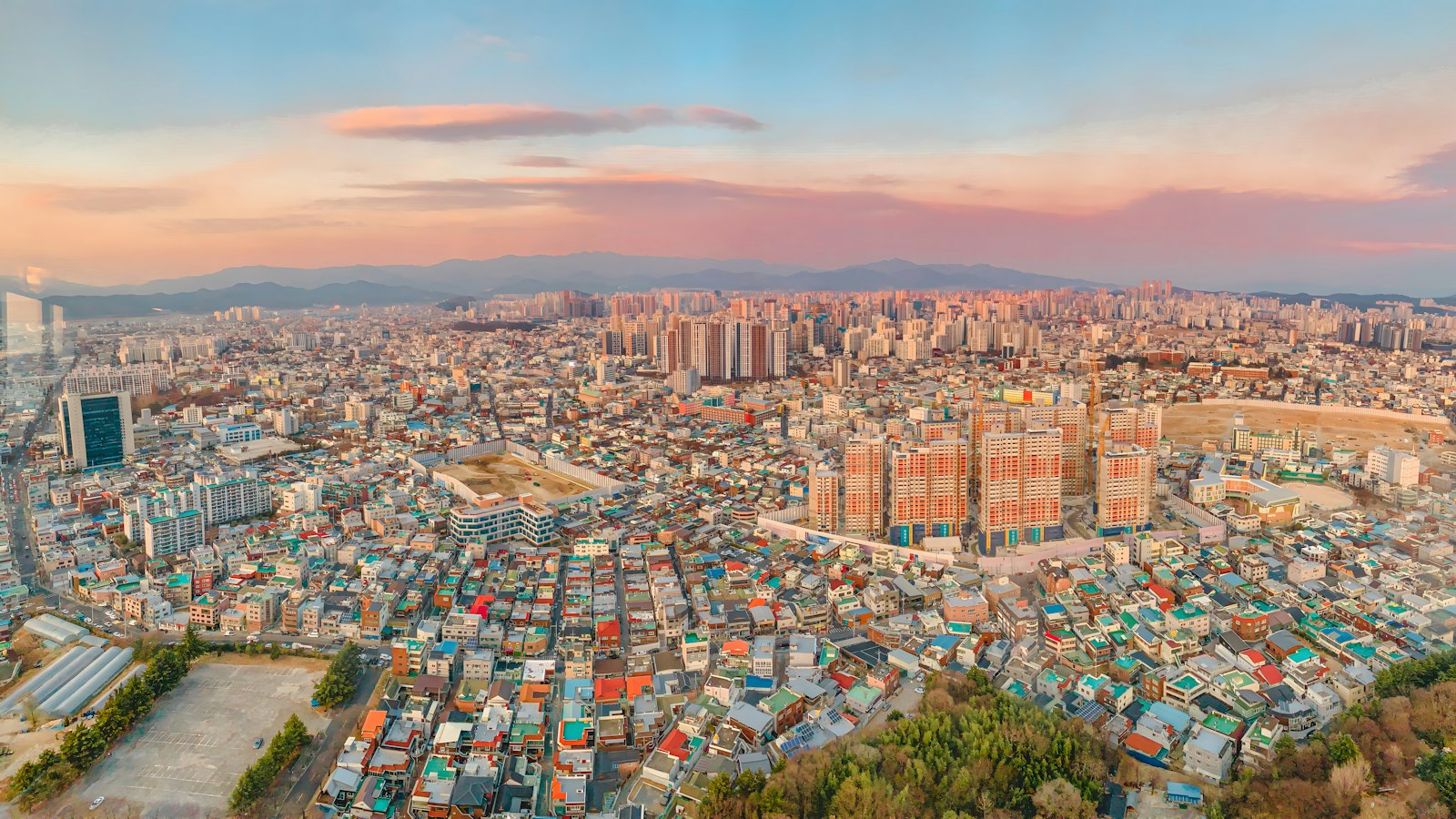 Daegu's skyline sprawling beneath a pink and orange sunset sky
