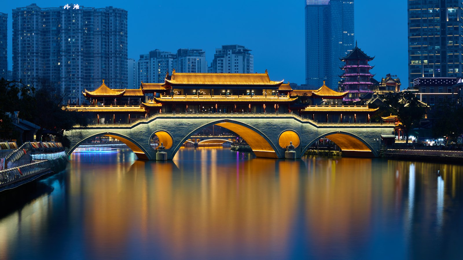 Anshun Covered Bridge glowing gold over the Jin River at blue hour in Chengdu, China
