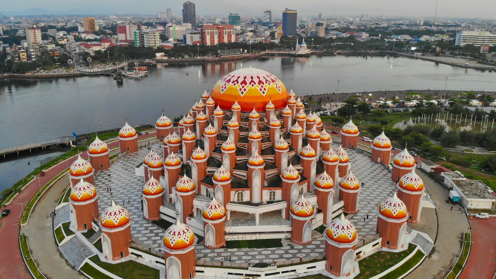 Aerial view of the 99-dome Al Asmaul Husna Mosque glowing orange at dusk in Makassar