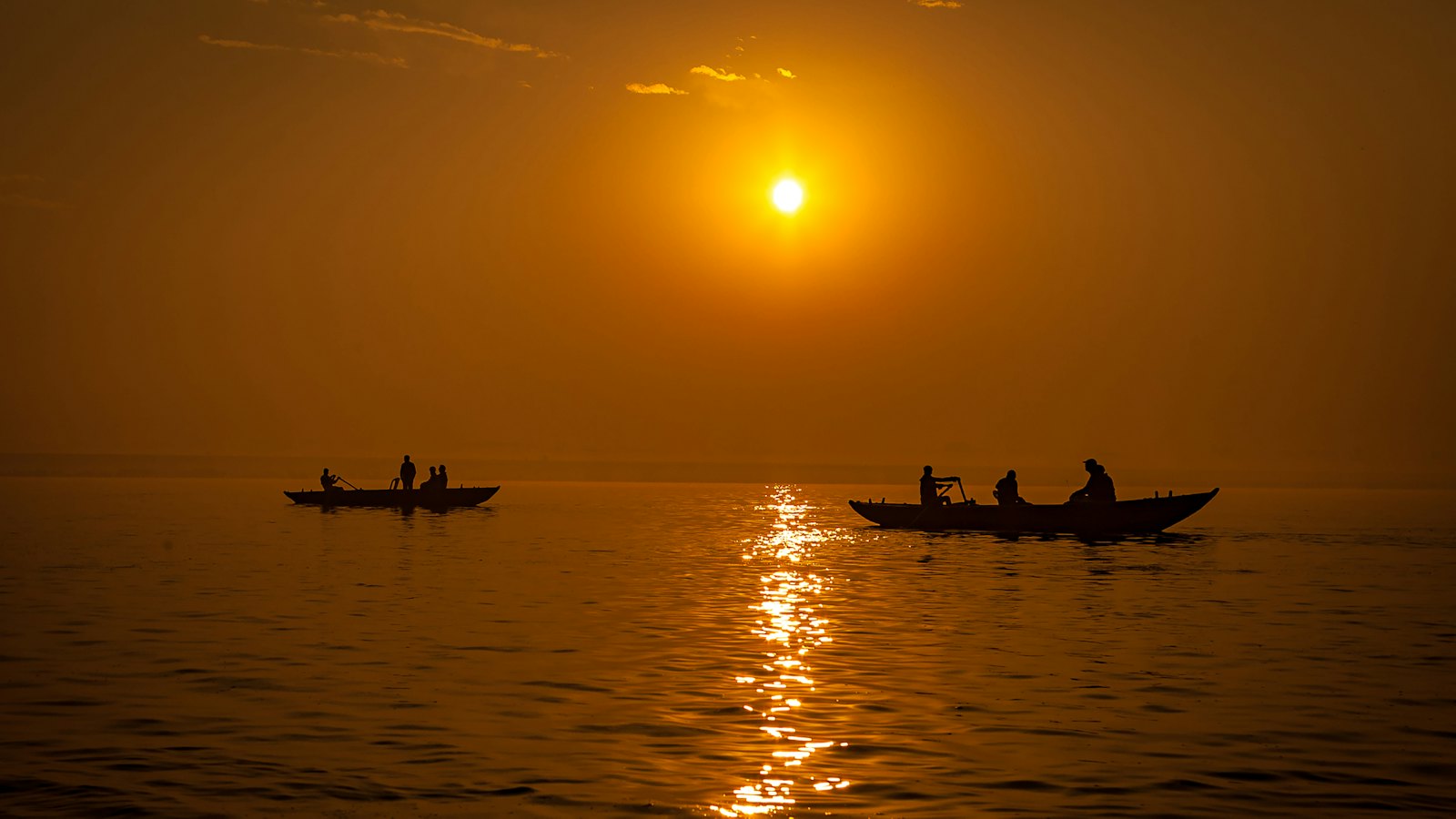 Silhouetted rowboats glowing on the Ganges River at sunset in Varanasi