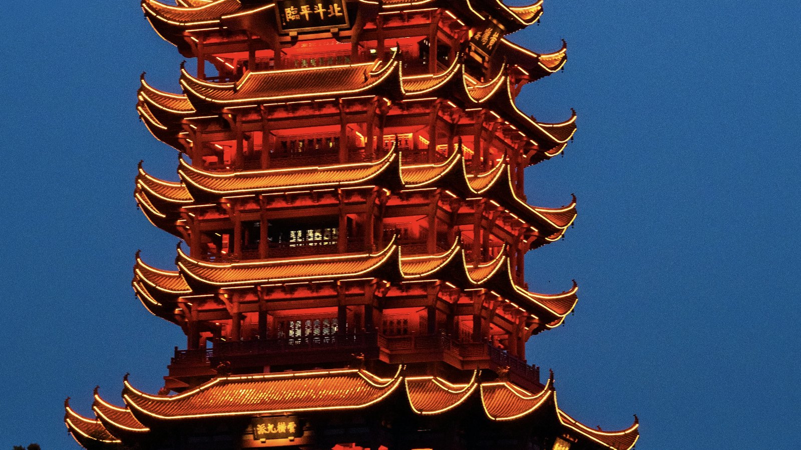 The Yellow Crane Tower glows red against a deep blue Wuhan evening sky