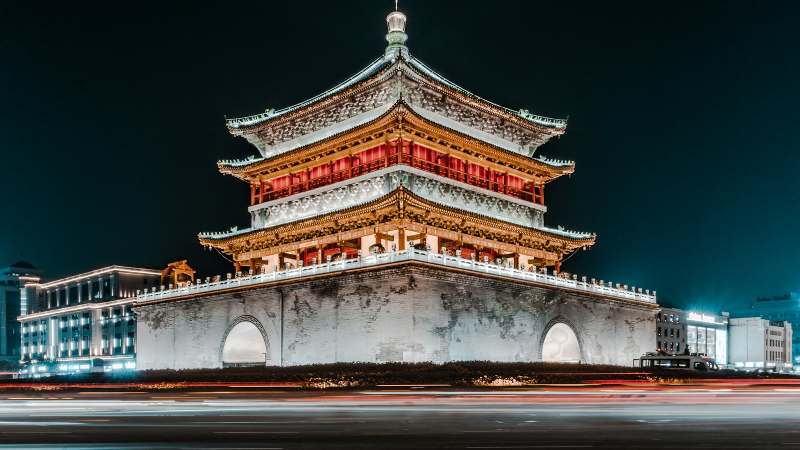 Xi'an Bell Tower illuminated at night above streaking traffic light trails in central Xi'an, China
